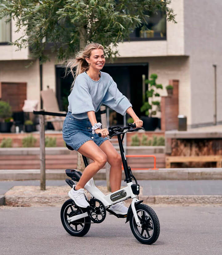 glad kvinde kører på el cykel inde i byen