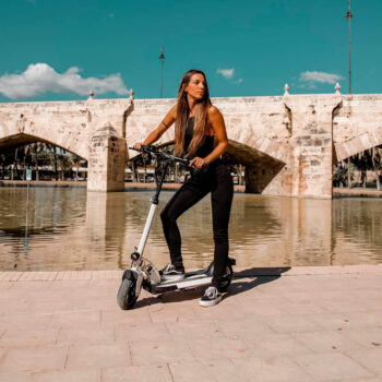 Kvinde står på skateflash sk3 el løbehjul ved vandet